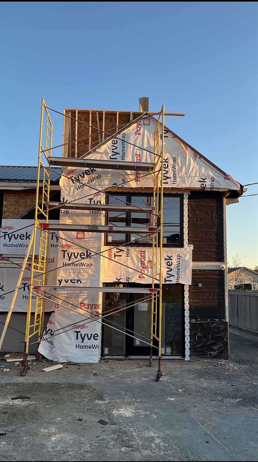 RevBuild Construction residential addition at sunset, wrapped and scaffolded