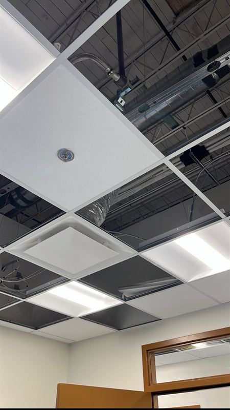 T-bar ceiling grid and tile being installed below exposed structure
